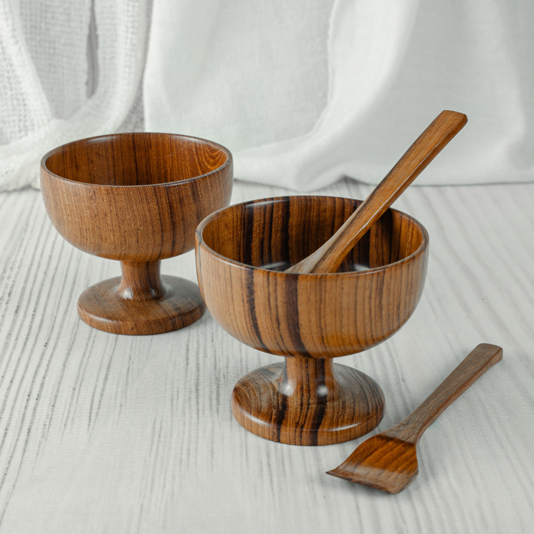 Two wooden bowls with a spoon on a light wooden surface