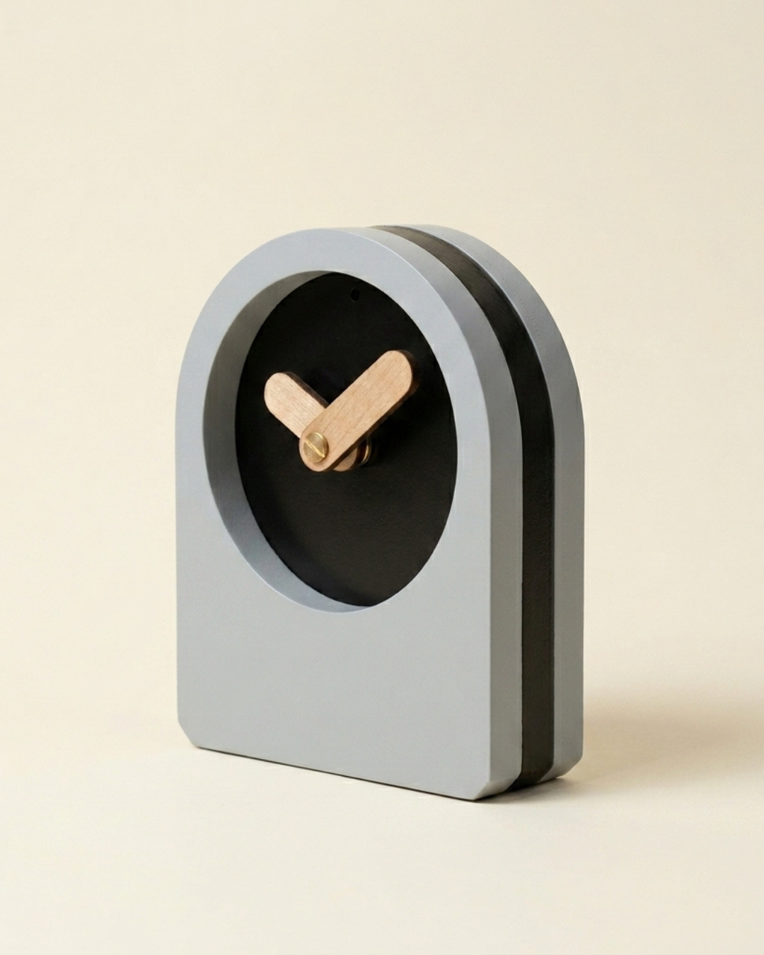 Modern clock with a gray casing and black face on a beige background