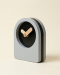 Modern clock with a gray casing and black face on a beige background
